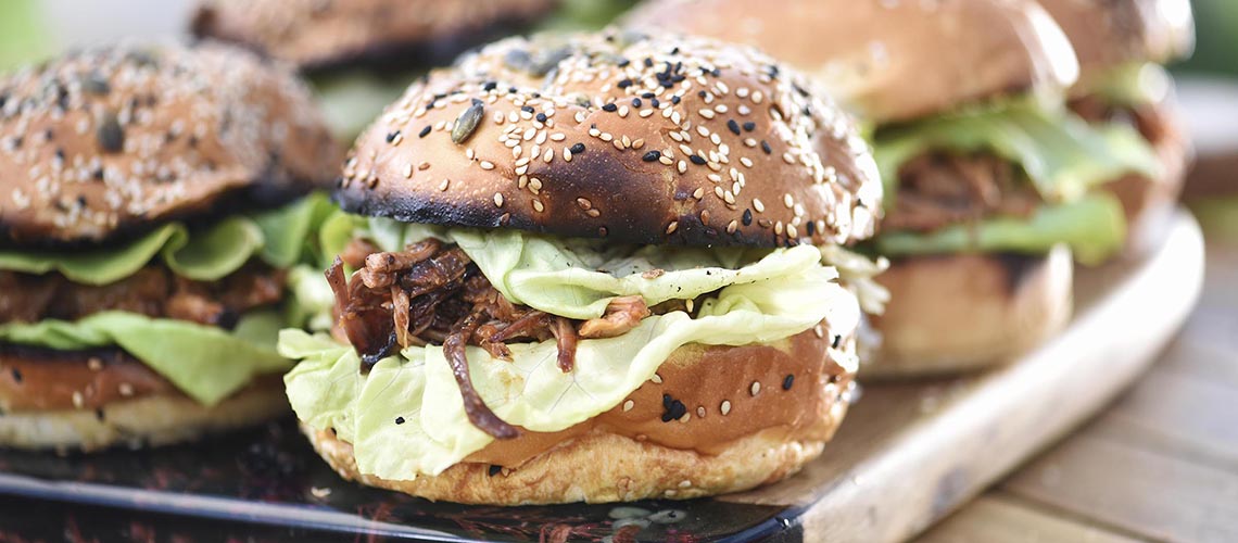 Burgeri cu carne de porc mărunțită (pulled pork), serviți pe tocător de lemn